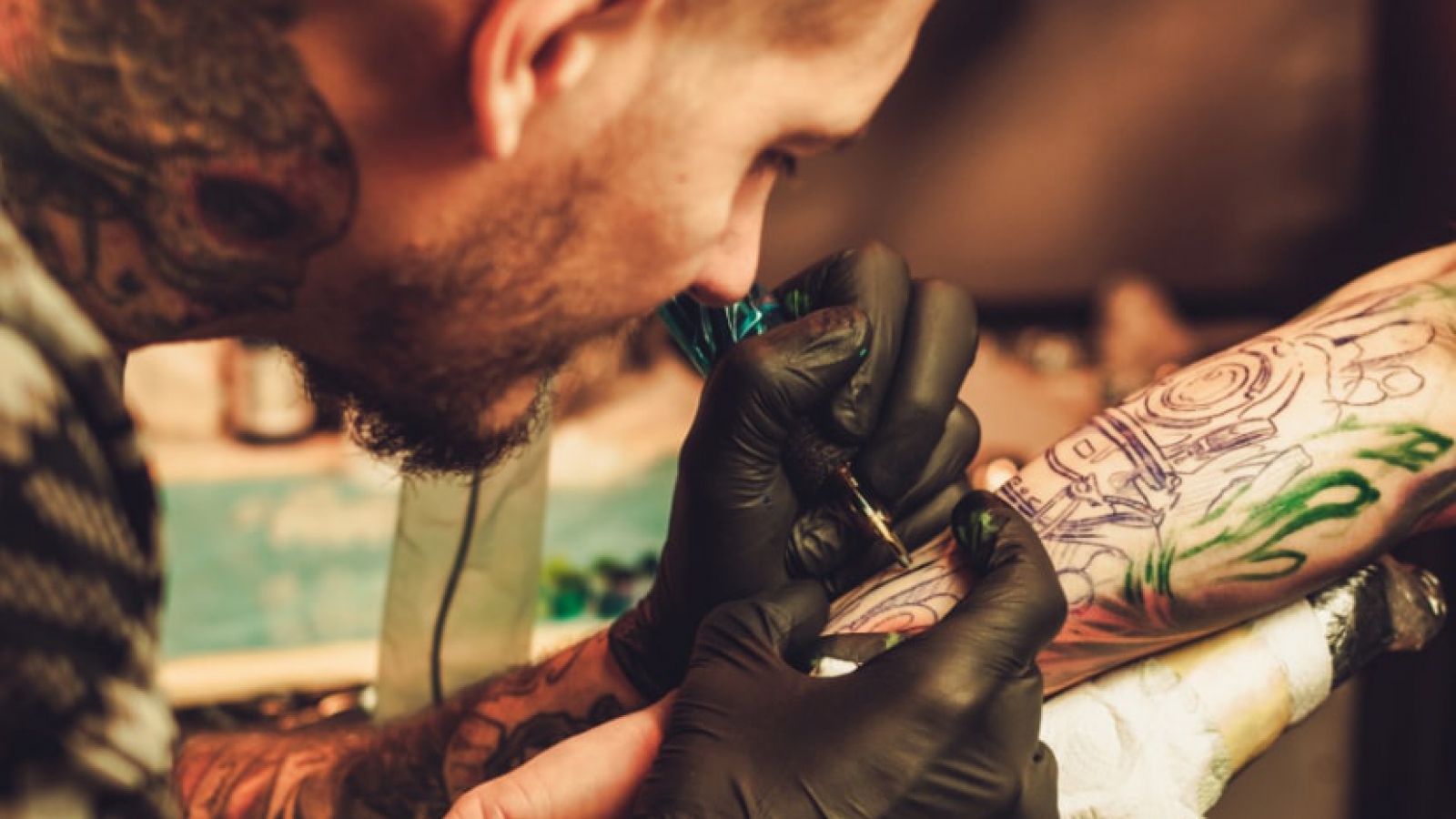 tattoo-artist-makes-a-tattoo-on-a-mans-hand-PECZRE223-min